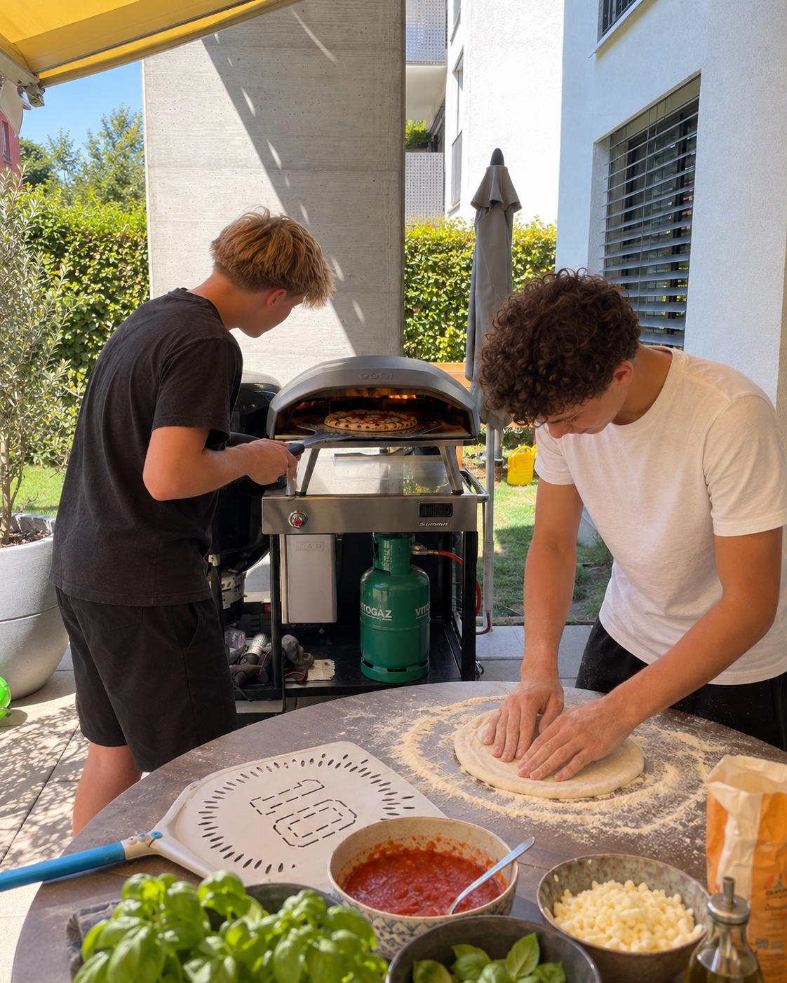 Zwei junge Pizzabäcker bereiten gemeinsam Pizza in ihrem Garten zu